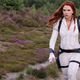 Scarlett Johansson as Natasha Romanoff in Marvel's Black Widow walking with purpose while wearing her white superhero suit.